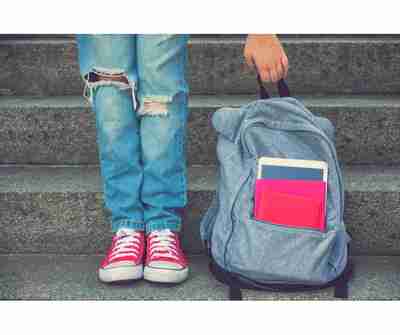 A student holding a backpack with school supplies in it.